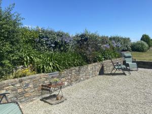 eine Terrasse mit 2 Stühlen und einer Steinmauer in der Unterkunft Holiday Home Cottage du Hamel es Clos by Interhome in Bretteville-sur-Ay