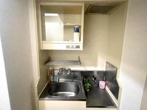 Una pequeña cocina con fregadero y espejo. en shibuya Honmachi Studio, en Tokio