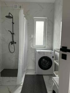 a white bathroom with a washing machine and a window at Aerodromas!Kunigiskiu K1 in Palanga