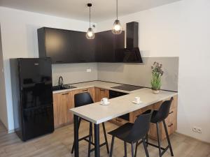 cocina con mesa y nevera negra en Exclusive Apartment - blisko Dworca, darmowy parking przy ulicy, późne wymeldowanie, Wi-Fi, en Opole