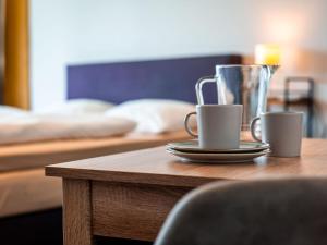 a wooden table with two coffee cups on a table with a bed at Ferienpark Geyersberg inklusive aktivCARD Bayerischer Wald in Freyung +35 photos