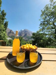a tray with a bottle of orange juice and a basket of oranges at The Backpackers' Nest Hunza in Hunza