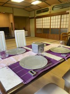 a table with plates and glasses on a purple table cloth at 門前屋 in Tokoname