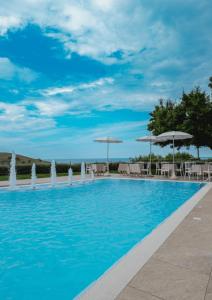 a swimming pool with blue water and umbrellas at Casa Ferretti di Ferretti Village in Silvi Marina