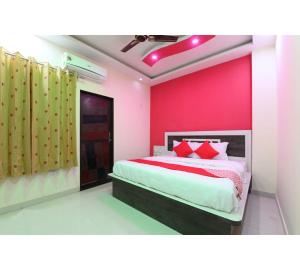 a bedroom with pink walls and a bed with red pillows at Hotel Lakhdatar Palace in Jaipur