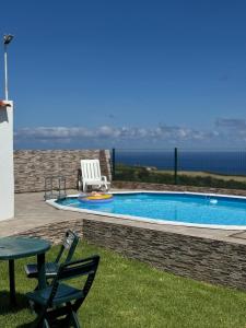 ein Swimmingpool mit zwei Stühlen und einem Tisch in der Unterkunft Northeast Azores, Rocha Mar House in Nordestinho