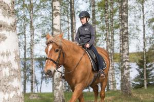 a young child riding on a horse in the woods at Villa Hauki, Puruvesi Lakeside by Naaranlahti in Naaranlahti