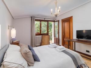 a bedroom with a large white bed and a television at Preciosa y amplia casa con piscina in Liendo