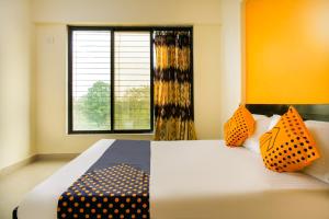 a bedroom with a bed with orange walls and a window at SPOT ON Pawan Villa in Gorhe