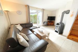 a living room with a leather couch and a fireplace at Am Waldwinkel Ferienhaus Sonne in Koserow