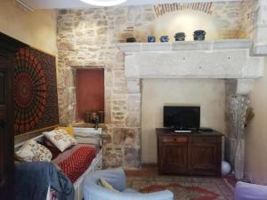 a living room with a stone fireplace with a couch and a television at Les Tomettes in Dole