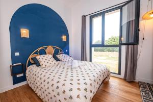 a blue bedroom with a bed and a large window at Gîte des Roussèles - Climatisation, Spa, jardin in Gaillac