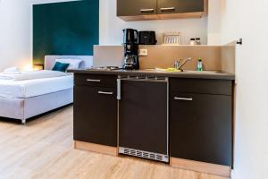 a small kitchen with a sink and a room with a bed at S17 Bude 13 Studio in Flensburg