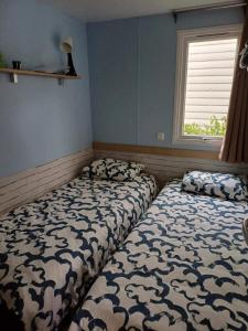 Dos camas sentadas en una habitación con ventana. en MOBIL HOME le WELCOM, en Valras-Plage