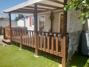 Una terraza de madera con toldo en una casa en MOBIL HOME le WELCOM, en Valras-Plage 3 fotos más