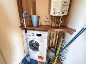 a laundry room with a washing machine on a shelf at 8 Berth Caravan With Decking At California Cliffs Near Scratby Beach Ref 50002E in Great Yarmouth