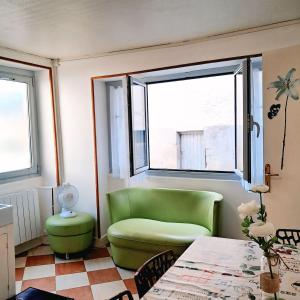 ein Wohnzimmer mit einem grünen Stuhl und einem Tisch in der Unterkunft La maison de la cité médiévale in Donzenac