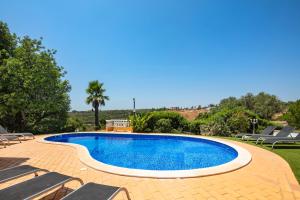 a swimming pool with chaise lounge chairs around it at Vivenda Vale Verde in Carvoeiro
