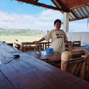 a man standing in front of a wooden table at Barrel cottages areguling in Kuta Lombok +9 photos