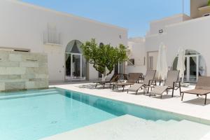 a swimming pool with chairs and a table and a building at Hydeout Palace - Luxury & Spa Suites by Wonderful Italy in San Vito dei Normanni