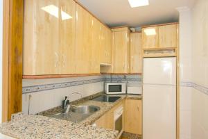 a kitchen with wooden cabinets and a sink and a refrigerator at Apartamento Jazmín in Fuengirola +14 photos