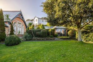 una casa con un giardino verde con un albero di Charming Summerhouse Annexe in lush gardens in Fowey a Fowey