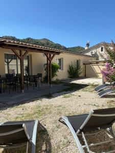 a patio with chairs and tables in a yard at Maison au calme avec terrasse in Saint-Julien-en-Saint-Alban