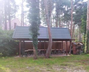 a log cabin with a table and chairs in the woods at Cyklami in Pobierowo +9 photos