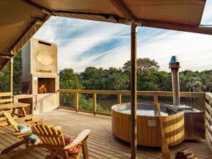 a deck with a hot tub and a fireplace at AfriCamps at Bonamanzi Game Reserve in Hluhluwe