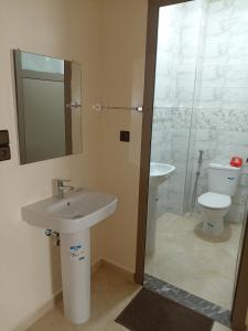 Un baño con lavabo, inodoro y espejo. en كراء يومي, en Aourir