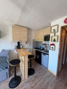 una piccola cucina con tavolo e due sgabelli da bar di Appartement cosy à la montagne aux pieds des pistes pour 4 personnes et 1 bébé a Taninges