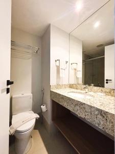 a bathroom with a toilet and a sink and a mirror at UniHome Niterói in Niterói