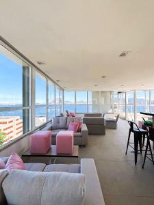 a living room with couches and tables and windows at UniHome Niterói in Niterói