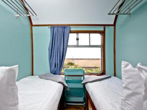 due letti in una piccola stanza con una finestra di Brunel Boutique Railway Carriage 4 a Dawlish Warren
