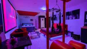 a living room with a room with pink lighting at Loveroom Very Good Trip chambre avec jacuzzi privatif in Staple