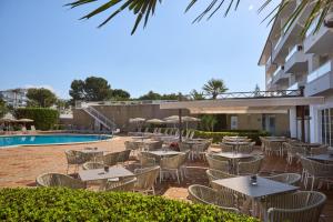 patio ze stołami i krzesłami przy basenie w obiekcie Grupotel Alcudia Suite w Playa de Muro