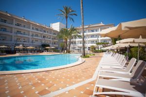 basen z krzesłami i parasolami obok budynku w obiekcie Grupotel Alcudia Suite w Playa de Muro
