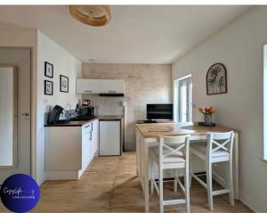 eine Küche mit einem Tisch und eine Küche mit weißen Geräten in der Unterkunft L'Oasis by Cozylife - Centre Ville in Niort