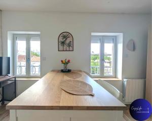 ein großer Holztisch in einem Zimmer mit zwei Fenstern in der Unterkunft L'Oasis by Cozylife - Centre Ville in Niort + 15 Fotos