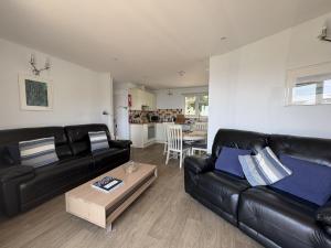 a living room with a black leather couch and a table at View of the Sea - Mount Brioni in Downderry
