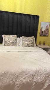 1 cama blanca grande con cabecero negro y almohadas en Harmony Spaces, en Kempton Park