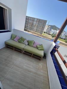 a couch with pillows sitting on a balcony at Joli et confortable appartement in Cabo Negro