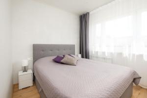 een witte slaapkamer met een groot bed met paarse kussens bij Mainiidu Apartment in Pärnu