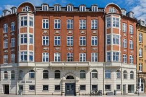 a large red brick building with many windows at Aalborg Apartment Centralt Beliggende med Moderne Faciliteter in Aalborg