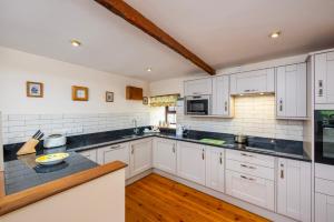 a kitchen with white cabinets and black counter tops at Wheal Kitty nr Truro in Truro
