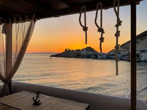 FiropótamosHada seaside apartment的从餐厅窗户欣赏日落时的海景