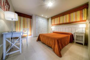a bedroom with a bed and a table and a desk at Apartamentos Piedramar in Conil de la Frontera