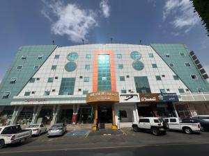 a large building with cars parked in a parking lot at Najma Roz Hotel in Abha