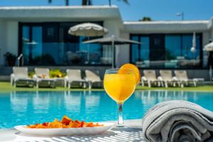 a glass of orange juice and a plate of food next to a pool at Bungalows Doña Rosa in Playa del Ingles