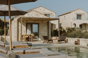 a patio with chairs and an umbrella and a pool at Beautiful Preveza Villa Villa Soleil 1 Bedroom Private Pool And Stunning Sea Views Kanali Beach in Preveza